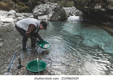 Outdoor Adventures On River. Gold Panning, Search For Gold. Man Is Looking For Gold With A Gold Pan In A Mountain Creek