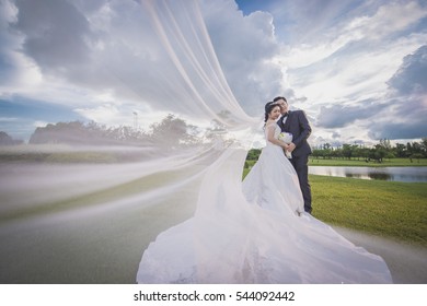 outdoor asian wedding under a cloudy sky on a green grass field