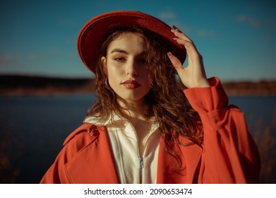 Outdoor Autumn Fashion, Lifestyle Portrait Of Beautiful Elegant Woman Wearing Trendy Orange Trench Coat, Hat, Posing In Nature. Copy, Empty Space For Text