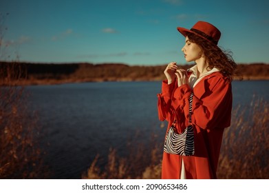 Outdoor Autumn Fashion Portrait Of Elegant Woman Wearing Trendy Orange Trench Coat, Hat, Holding Zebra Print Faux Leather Handbag, Posing In Nature.  Copy, Empty Space For Text