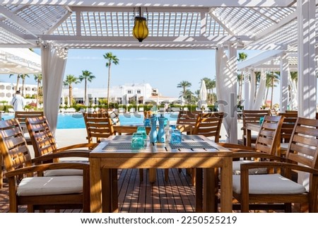 Outdoor bar of hotel in Sharm el sheikh with swimming pool, wooden tables and chairs