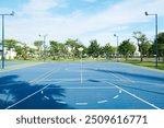 An outdoor basketball court on a sunny day with clouds.