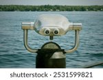 Outdoor binoculars overlooking the St. Lawrence Seaway to the United States side of the river from the Brockville Municipal Marina Ontario Canada.