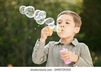 Outdoor, bubbles and blow of boy for playful, excitement and entertainment for childhood in park. Physical activity, imagination and creativity of kid with plastic toy, soap and movement in nature - Powered by Shutterstock