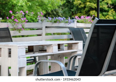 Im Freien befindet sich ein Café im Inneren der Straße, mit Holzmöbeln, roten Stühlen und kreativen Holzpalettentischen. Selektiver Fokus.