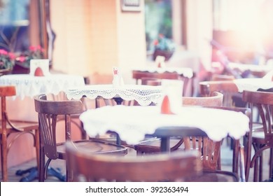 An outdoor cafe with vintage chairs, tables, white table cloths.