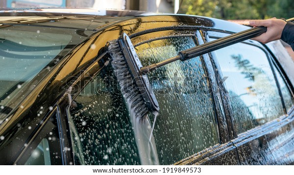 Outdoor car washing with a brush. Car window detail\
washing with a foam.