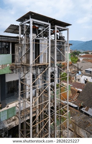 Outdoor cargo elevator structure on an old urban building background, industrial lift with steel frame construction, hoist mechanisms for vertical transport goods or construction materials