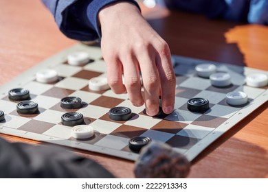 Outdoor Checkers Tournament On Paper Checkerboard On Table, Close Up Players Hands. Outdoor Draughts Board Game Between Two Amateur Players At Sunny Day, Development Of Strategic Thinking