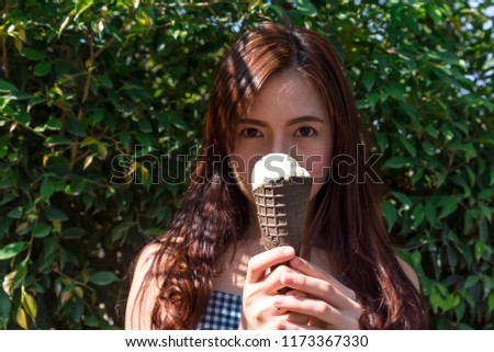Outdoor closeup fashion portrait of young hipster crazy eating ice cream in hot weather have fun and good mood. asian women eating a delicious ice cream in summer good mood looking and smiling.