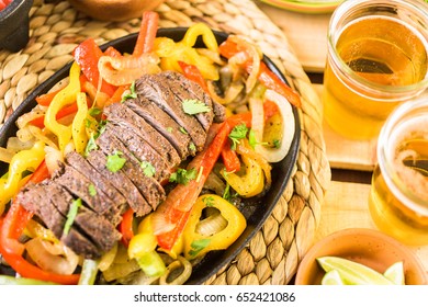 Outdoor Cooking. Steak Fajitas With Bell Peppers And Yellow Onion On A Cast Iron Fajita Skillet.