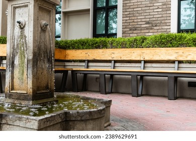 Outdoor court yard with small water fountain with spouts and surrounding benches, copy space