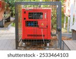 Outdoor diesel power generator. Power supply generator placed on street sidewalk. Small business generators in autumn. Sunny day.