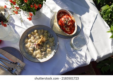 Outdoor Dining Gnocchi With A Mushroom Cream Sauce, Spinach And Lasagna With Tomato Sauce On A White Sheet Table In The Garden. Authentic Italian Food In The Overhead Shot With White Wine