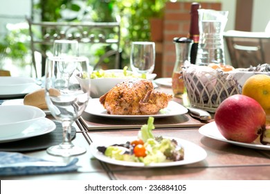 An outdoor dining meal complete with roast chicken, salad, bread rolls, wine and fruit in summer. Concept of outdoor dining. - Powered by Shutterstock