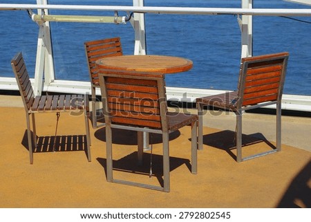An outdoor dining set consisting of a table and chairs with a stainless steel frame and wooden slats. An outdoor terrace on the ferry deck.