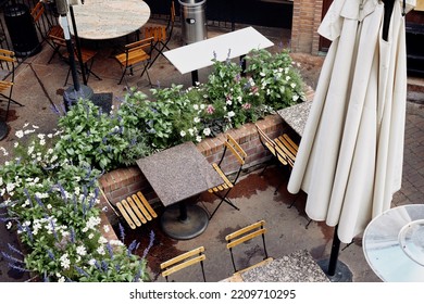 Outdoor Dining Tables At A Restaurant With String Lights Hanging Above Located In A Shopping Plaza.  