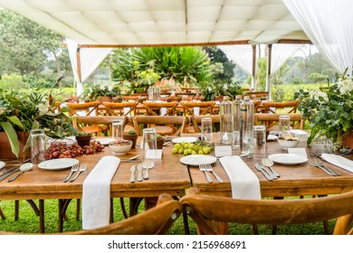 An outdoor dinner party venue with arranged wooden tables