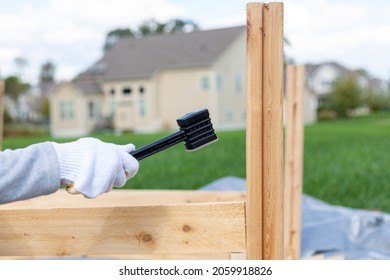 Outdoor Diy Project In Backyard With Lawn. A Person Wearing Safety Gloves Is Installing A Wooden Fence Or Furniture Using A Plastic Hammer To Tighten. Concept Image For Worker, Wood Work.