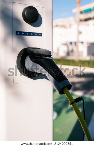 Outdoor electric car charger with houses and gardens\
in the back