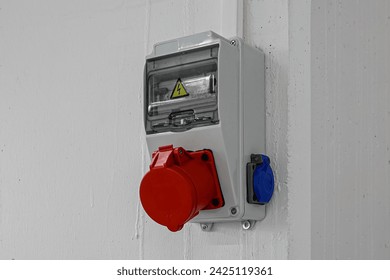 Outdoor Electrical Box with Single and Three Phase Current Electrical Appliances and Power Outlets. Three phase connectors. In a factory hall, red and blue, 220 volt and 380 volt sockets.