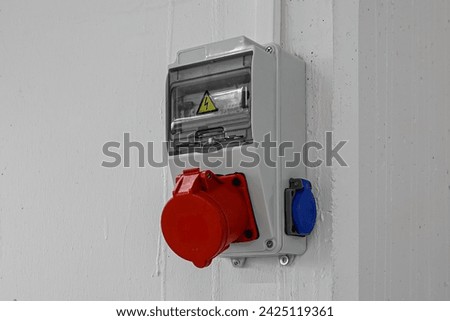 Outdoor Electrical Box with Single and Three Phase Current Electrical Appliances and Power Outlets. Three phase connectors. In a factory hall, red and blue, 220 volt and 380 volt sockets.