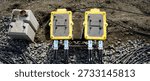 Outdoor electrical junction boxes with multiple cables laid on gravel ground, showing temporary power distribution, industrial setup, and construction site infrastructure.