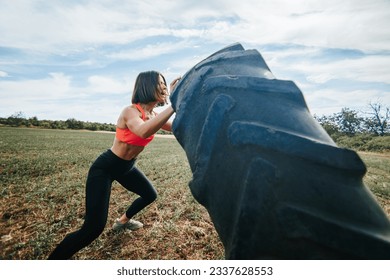 Outdoor exercise session with a Cross Fit fitness woman lifting a wheel. Strength and Determination Cross Fit Woman Lifting a Wheel Outdoors - Powered by Shutterstock