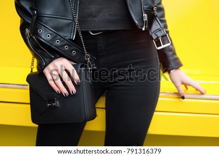Outdoor fashion details.close up fashion details. perfect spring outfit acessories. young fashion blogger holding her trendy brown handbag. perfect elegant purse.Yellow urban background