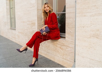 Outdoor fashion photo of elegant  blond woman posing on the street. Wearig casual red velvet dress. 