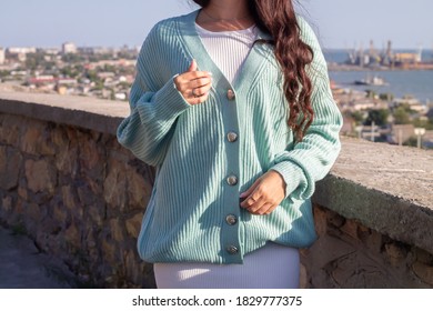 Outdoor fashion photo of young beautiful woman in sea landscape. Lady in warm knitted stylish cardigan