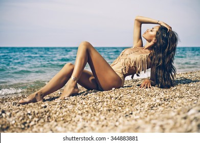 Outdoor fashion portrait of tanned lady in sexual swimsuit posing at beach