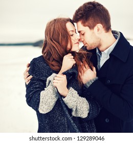 Outdoor Fashion Portrait Of Young Sensual Couple In Cold Winter Wather. Love And Kiss