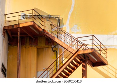 Outdoor Fire Exit Stair Of Old Yellow Building. Rusty Fire Escape Metal Stair.