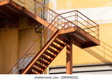 Outdoor Fire Exit Stair Of Old Yellow Building. Rusty Fire Escapes Metal Stair.