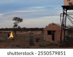 Outdoor Fire with Traditional Sheds and Water Tanks with Blue Sky Backdrop