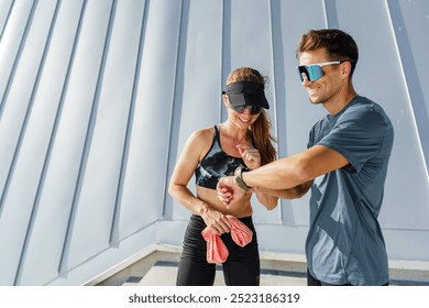 Outdoor Fitness Enthusiasts Checking Their Workout Performance on a Sunny Day at a Rooftop Gym - Powered by Shutterstock