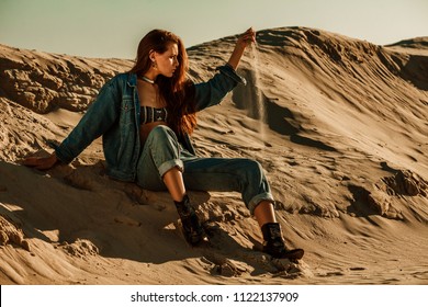 Outdoor Full Body Portrait Of Young Beautiful Fashionable Woman Wearing Stylish Denim Jacket, Jeans, Cowboy Boots, Posing On The Sand. Copy, Empty Space For Text