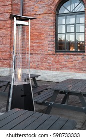 Outdoor Gas Heater Stands Near Wooden Tables On Restaurant Terrace 