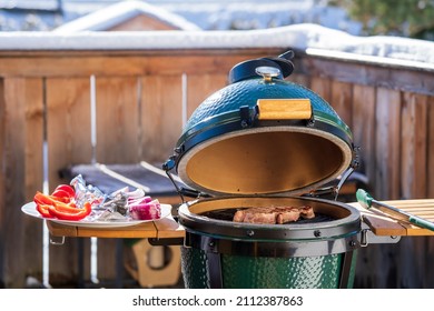 outdoor grilling a staek with onions on a ceramic grill with charcoal at a winter day