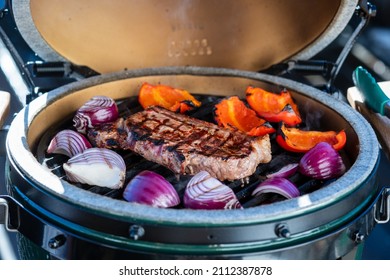 outdoor grilling a staek with onions on a ceramic grill with charcoal at a winter day