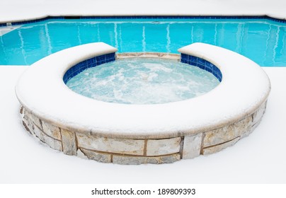 Outdoor Hot Tub Or Spa By Swimming Pool Surrounded By Snow In The Winter