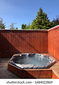 Outdoor Hot Tub In A Wooden Enclosure Under A Blue Sky