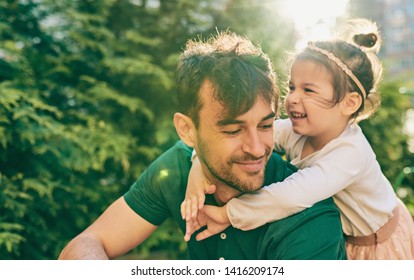 Outdoor image of happy cute little girl smiling and playing with her father. Handsome dad and pretty kid having fun and playing at playground. Daddy and daughter shares love together. Fatherhood - Powered by Shutterstock