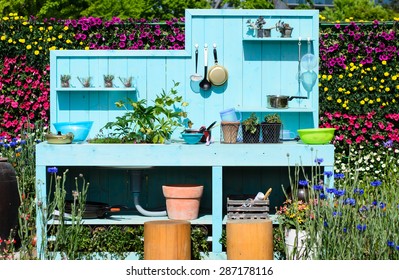 Outdoor kitchen, Kitchenware on blue wooden wall, kitchen in the flowers garden.