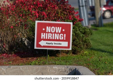 Outdoor Lawn Sign Now Hiring Apply Inside With Direction Arrow, Selective Focus. Great Resignation, Employment, Understaffed Business, Work Strikes, Absent Workers Due To Covid Labor Shortage Concept.