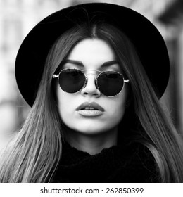 Outdoor Lifestyle Portrait Of Pretty Funny Hipster Woman. Modern Urban Girl Having Fun. Beautiful Young Girl In A Hat. Black And White Portrait.