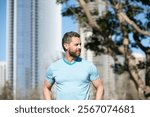 Outdoor male portrait. Man in blue t-shirt posing near American city. Happy business man posing outside. Businessman. Business man in t-shirt. American owner, casual businessman.