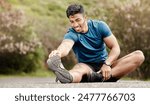 Outdoor, man and stretching leg for fitness, training and exercise for wellness with balance. Nature, road and Indian person or runner with warm up, preparation and getting ready for sports challenge