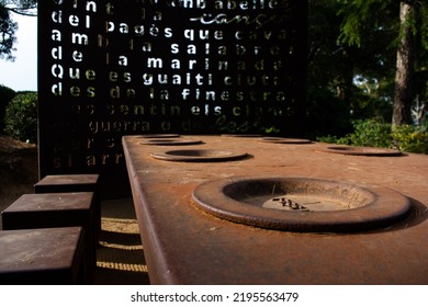 An Outdoor Metal Table, With Dishes Anchored And Ready To Fill With Food.